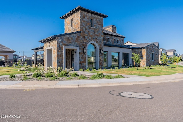 contemporary house featuring stone siding, a chimney, and a front yard