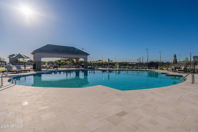 community pool with fence, a patio area, and a gazebo