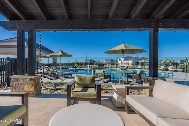 view of patio / terrace featuring a community pool, fence, and outdoor lounge area