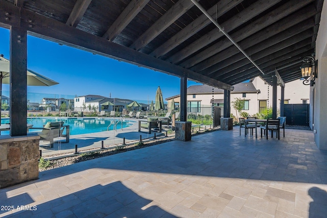 community pool with a patio, fence, and outdoor dining space