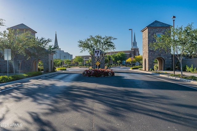 view of asphalt road featuring traffic signs, street lights, and curbs