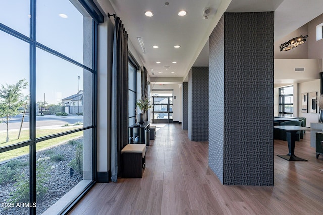 hall featuring wood finished floors, an accent wall, and recessed lighting