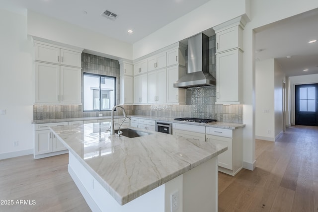 kitchen featuring wall chimney exhaust hood, a sink, gas stovetop, white cabinetry, and recessed lighting