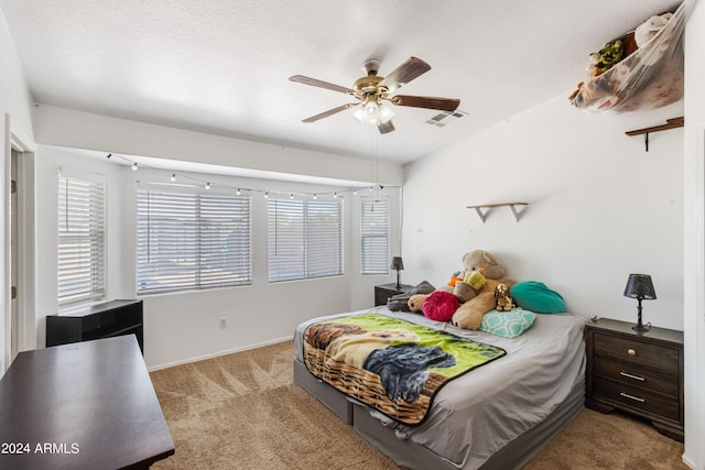 carpeted bedroom featuring ceiling fan and a textured ceiling