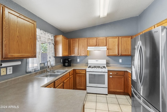 kitchen with stainless steel fridge, vaulted ceiling, light tile patterned floors, white gas stove, and sink