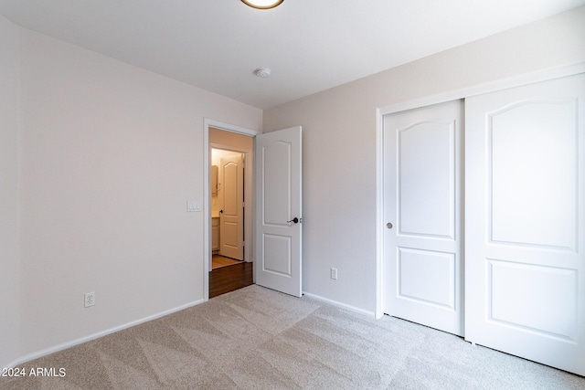 unfurnished bedroom with a closet and light carpet