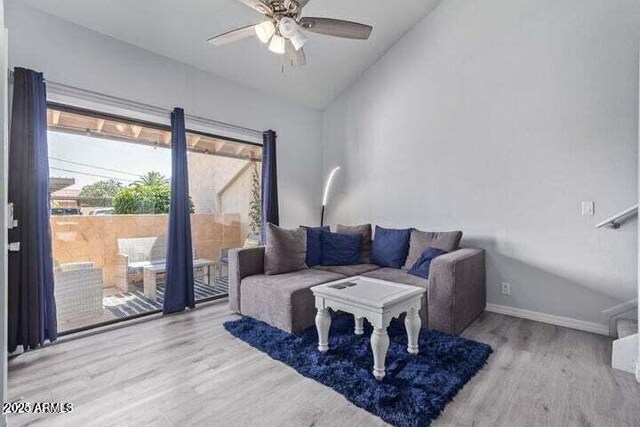 living room featuring baseboards, lofted ceiling, wood finished floors, and ceiling fan