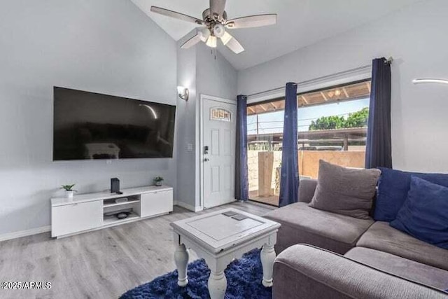 living area featuring baseboards, ceiling fan, high vaulted ceiling, and light wood-style flooring