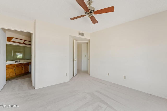 unfurnished bedroom featuring visible vents, a ceiling fan, connected bathroom, light colored carpet, and a sink