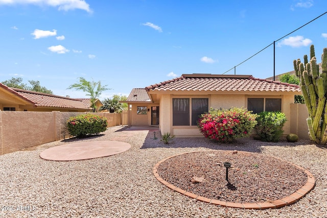 rear view of house with a patio, a tile roof, fence, and stucco siding