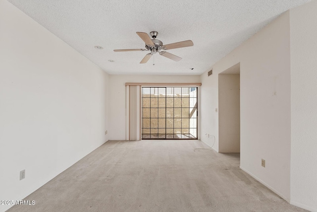 spare room with carpet floors, visible vents, a textured ceiling, and a ceiling fan