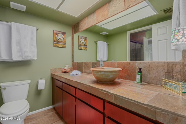 bathroom with hardwood / wood-style flooring, vanity, a shower, and toilet