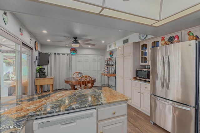 kitchen featuring appliances with stainless steel finishes, stone countertops, white cabinets, ceiling fan, and light wood-type flooring