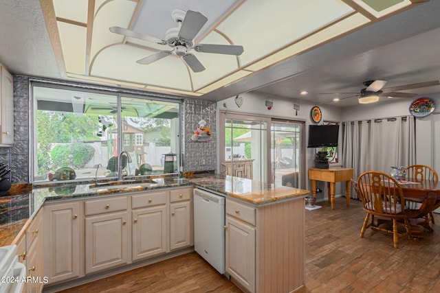 kitchen with sink, dark stone counters, kitchen peninsula, white appliances, and light hardwood / wood-style flooring