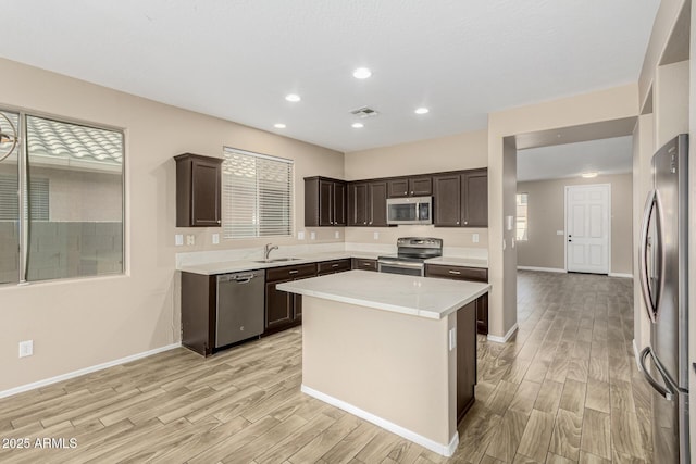 kitchen featuring sink, light hardwood / wood-style flooring, stainless steel appliances, a center island, and dark brown cabinetry