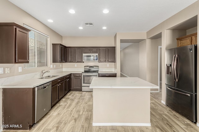 kitchen featuring stainless steel appliances, light hardwood / wood-style floors, sink, and a kitchen island