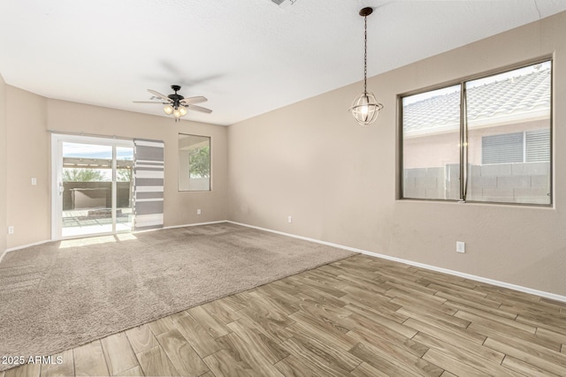 unfurnished room with ceiling fan with notable chandelier and light hardwood / wood-style floors