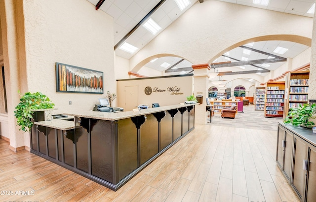 welcome area featuring high vaulted ceiling, arched walkways, a skylight, and a textured wall