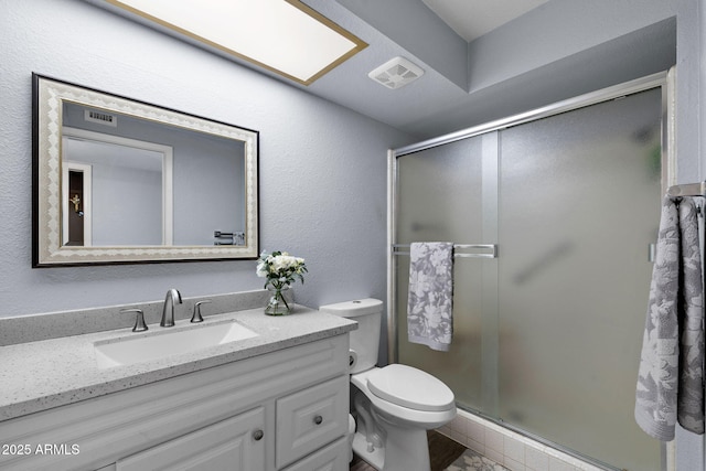 full bath featuring a stall shower, vanity, and toilet