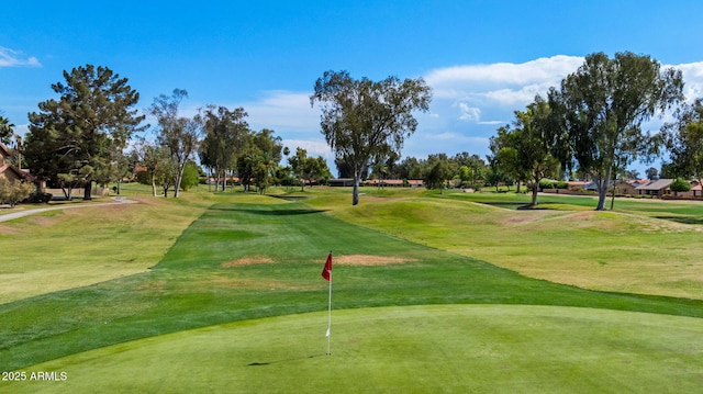 view of community with view of golf course, a yard, and a putting green