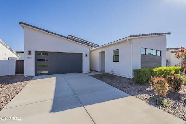 contemporary house featuring driveway, an attached garage, fence, and stucco siding