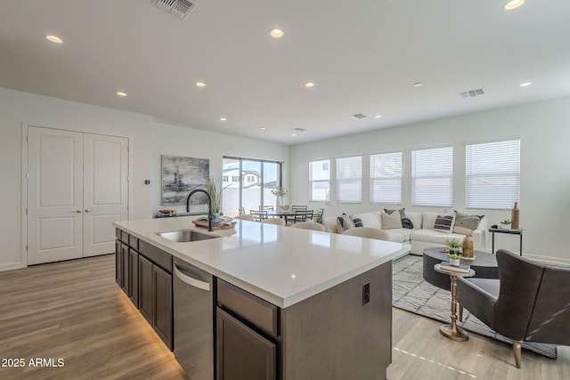 kitchen featuring a sink, light wood finished floors, visible vents, and dishwasher