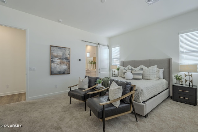 bedroom with a barn door, connected bathroom, light carpet, visible vents, and baseboards