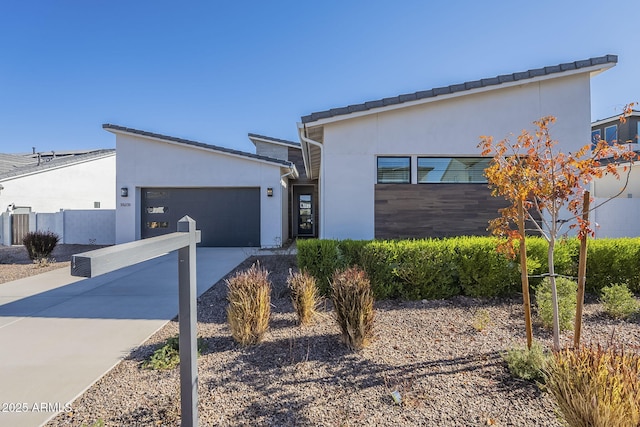 modern home with a garage, concrete driveway, and stucco siding