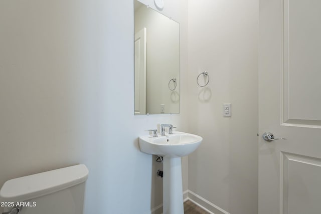 bathroom with baseboards, a sink, and toilet