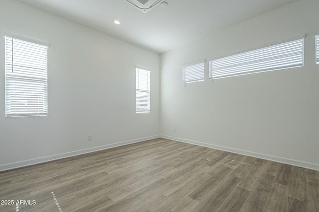 spare room featuring recessed lighting, light wood-style flooring, and baseboards