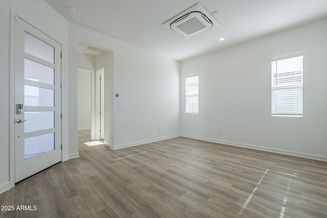 spare room with wood finished floors, visible vents, and baseboards