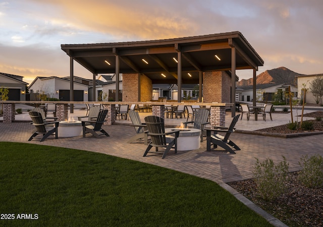 patio terrace at dusk featuring an outdoor fire pit and a yard