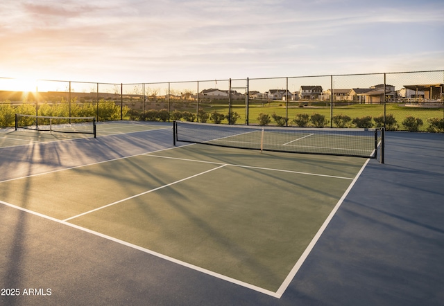 view of tennis court with a residential view and fence