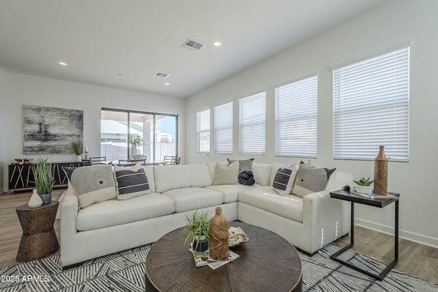 living room with recessed lighting, visible vents, baseboards, and wood finished floors