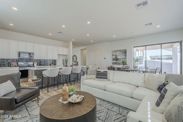 living room featuring recessed lighting, visible vents, and light wood-style flooring