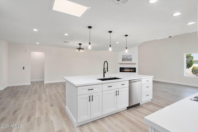 kitchen with pendant lighting, white cabinetry, dishwasher, sink, and an island with sink