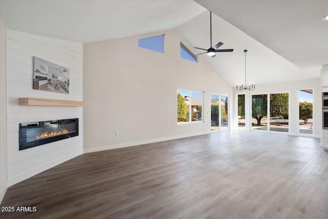 unfurnished living room featuring hardwood / wood-style flooring, a large fireplace, ceiling fan with notable chandelier, and high vaulted ceiling