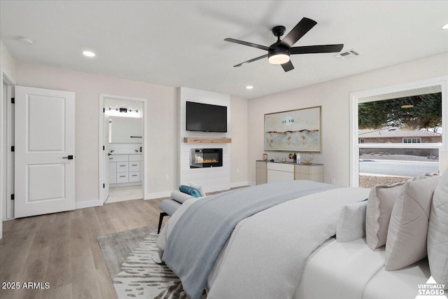 bedroom featuring ceiling fan, ensuite bath, and light hardwood / wood-style flooring