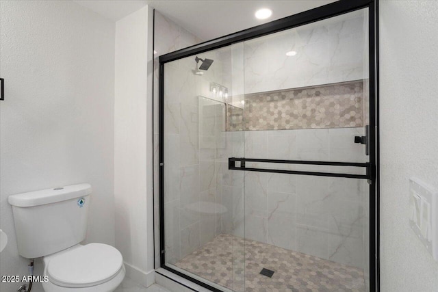 bathroom featuring toilet and a shower with shower door