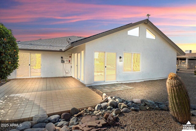 back house at dusk featuring a patio area