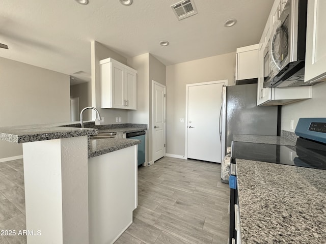 kitchen with white cabinetry, sink, a kitchen breakfast bar, kitchen peninsula, and appliances with stainless steel finishes