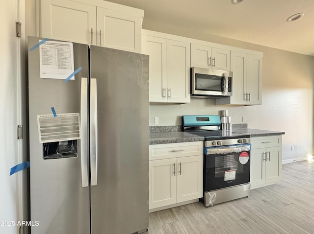 kitchen with appliances with stainless steel finishes, light hardwood / wood-style flooring, and white cabinetry