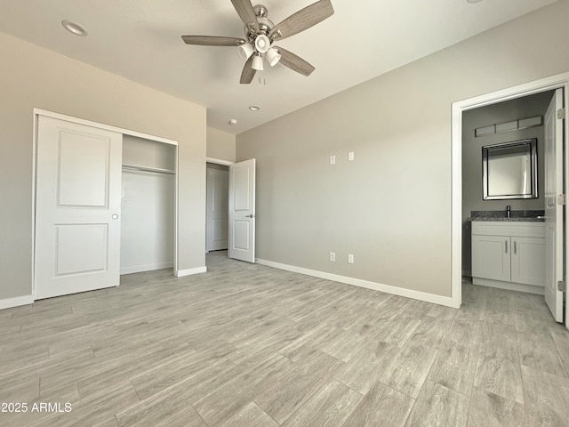 unfurnished bedroom featuring ceiling fan, sink, light hardwood / wood-style flooring, connected bathroom, and a closet