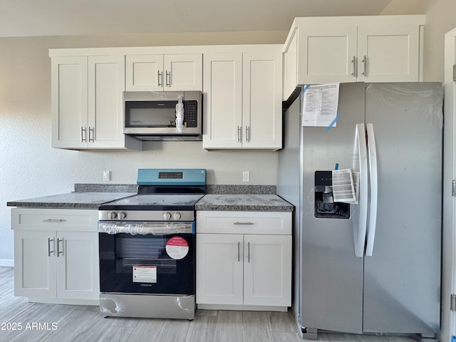 kitchen with light wood-type flooring, white cabinetry, and appliances with stainless steel finishes