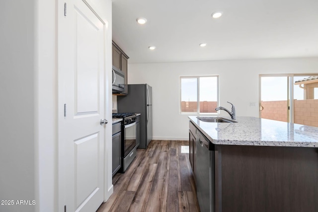 21999 E Wayward Ln, Red Rock, AZ 85145 - kitchen featuring appliances with stainless steel finishes, dark wood finished floors, recessed lighting, light stone counters, and an island with sink