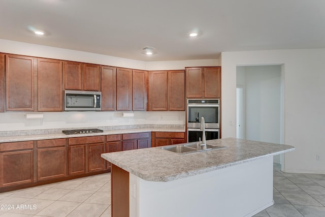 kitchen featuring a kitchen island with sink, sink, light tile patterned floors, and appliances with stainless steel finishes