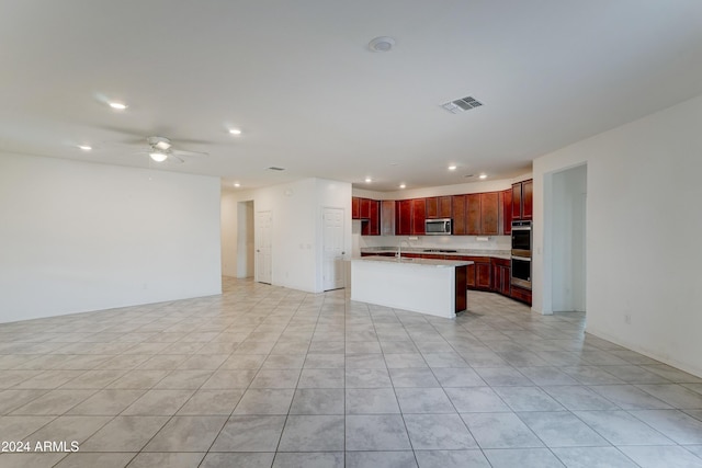 kitchen featuring decorative backsplash, appliances with stainless steel finishes, ceiling fan, light tile patterned floors, and an island with sink