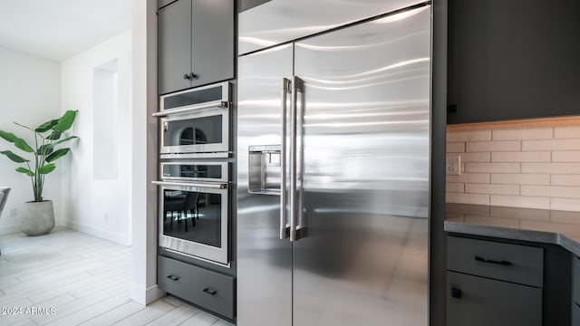 kitchen with appliances with stainless steel finishes, light hardwood / wood-style floors, and tasteful backsplash