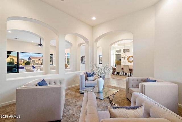 living room featuring baseboards, carpet flooring, recessed lighting, ceiling fan with notable chandelier, and arched walkways
