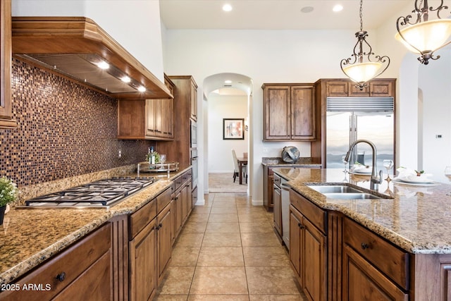 kitchen with premium range hood, a sink, tasteful backsplash, stainless steel appliances, and arched walkways
